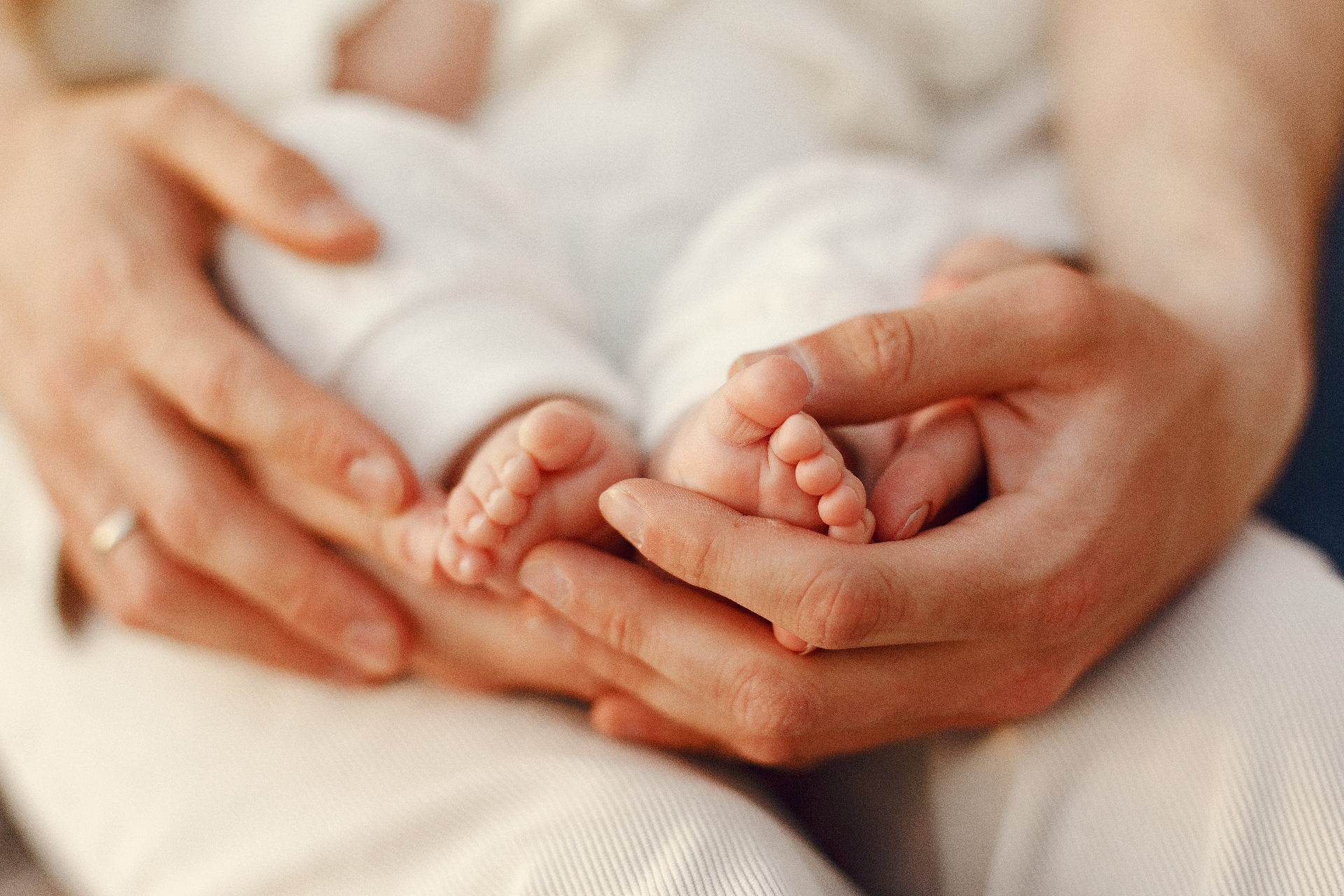 Mains d'adulte tenant les pieds d'un bébé
